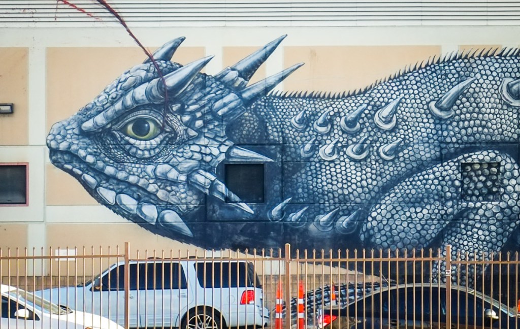 close up of head on ROA street art mural of a giant horned lizard.  open eye, spikes on head, blunt nose, 