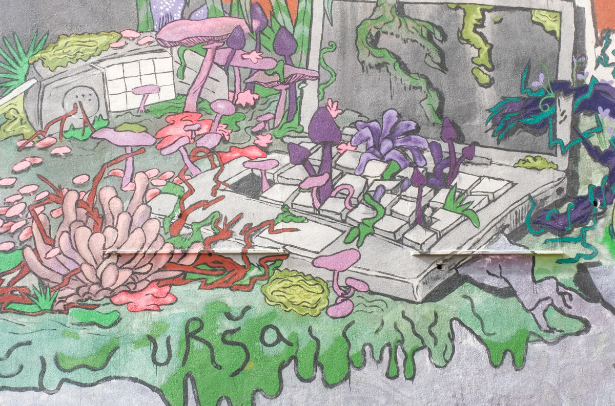 mural of an old flip phone and open laptop that have begun to sprout new growth