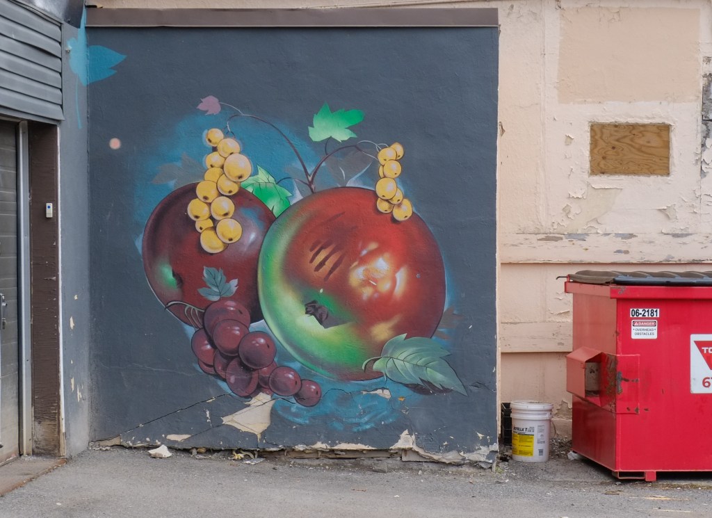 mural on an exterior wall, blue background, two large red apples with two bunches of yellow currants, 