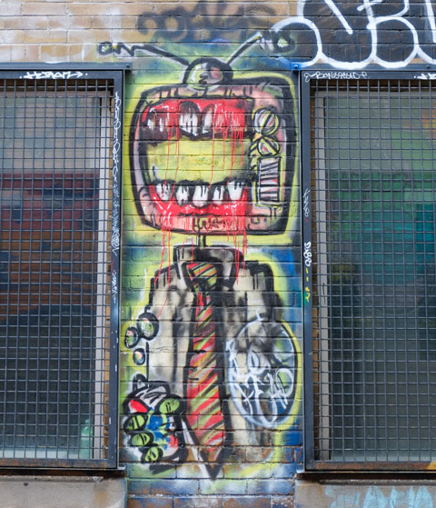 graffiti painting by bone head on a brick wall in the narrow space between two windows, large boney head, narrow white shirt and striped neck tie