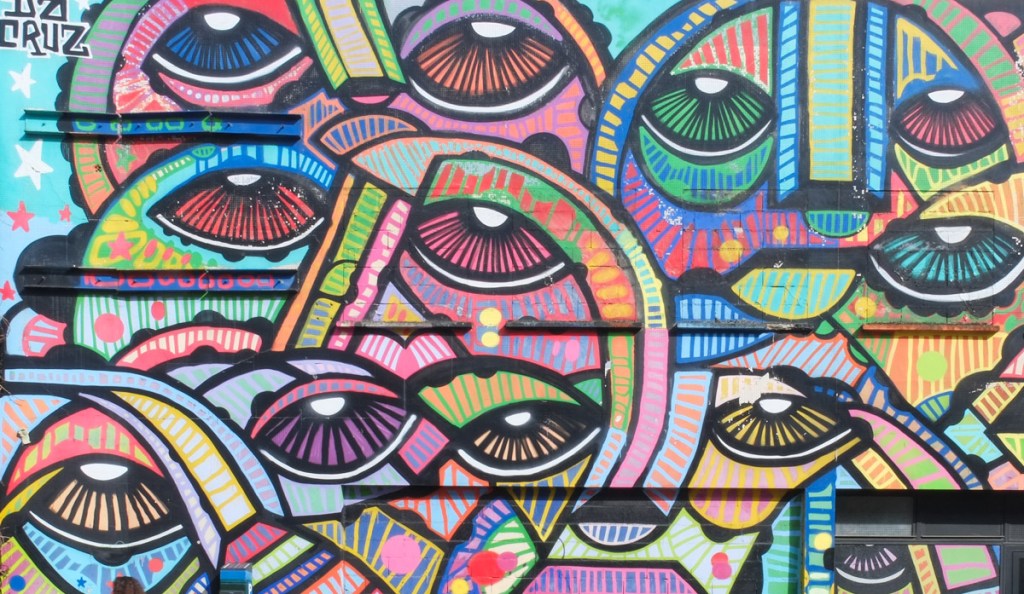 close up of part of mural by d a cruz of bright coloured faces and eyes