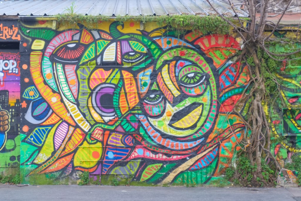 two very stylized faces, a street art painting by d a cruz