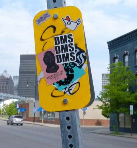 graffiti stickers on a yellow sign