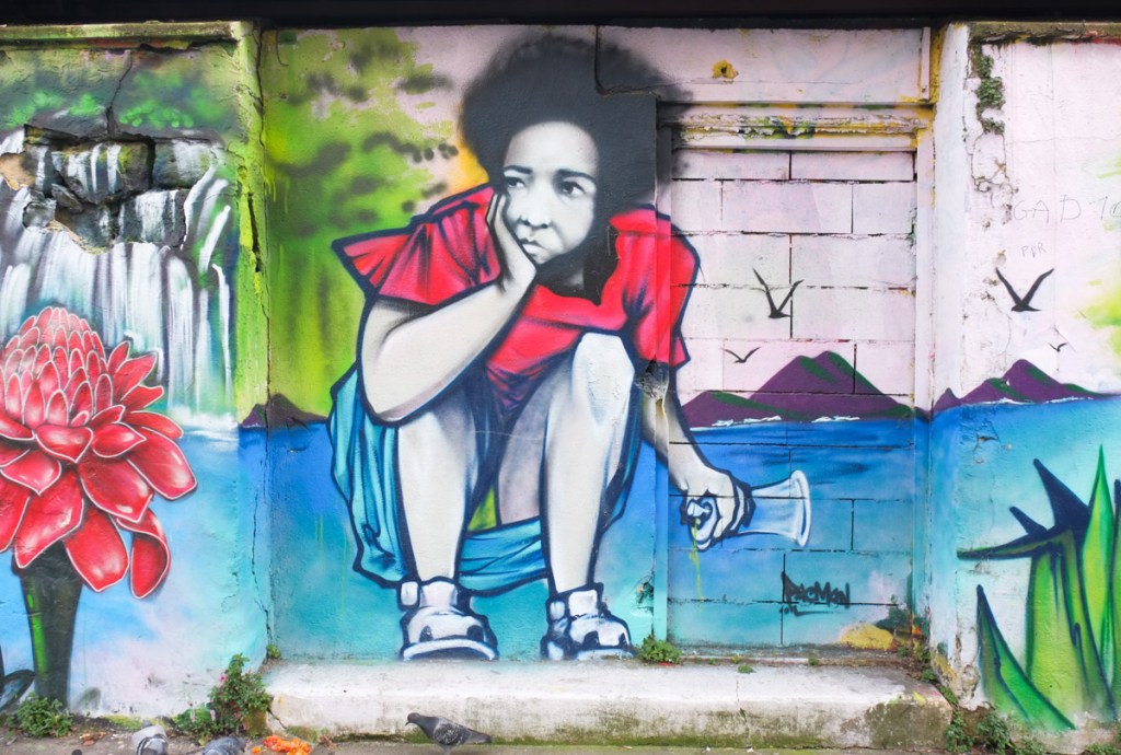 a street art painting of a woman squatting on the ground, with a spray paint can in her hand