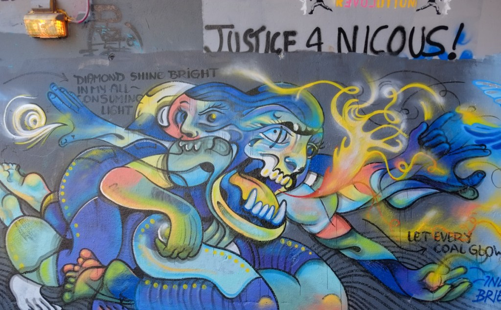 street art painting under a railway bridge in blues and greens