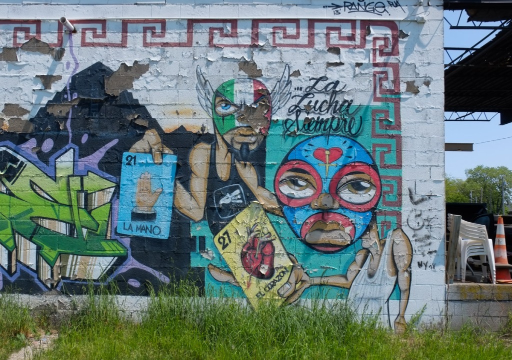 mural with Mexican fighters and the words La Lucha Siempre, also playing cards with el corazon (heart) and la mano (hand).  One fighter has mask in green, white, and red stripes, the same colours as the Mexican flag