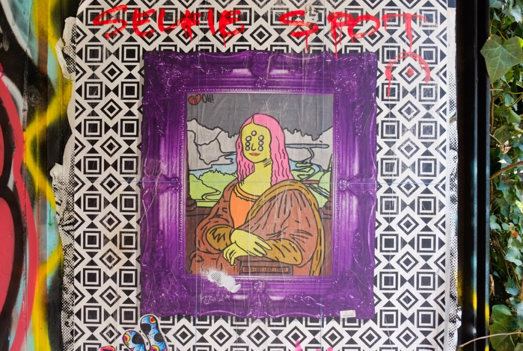 pasteup graffiti of a version of the Mona Lisa painting, framed in purple and white
