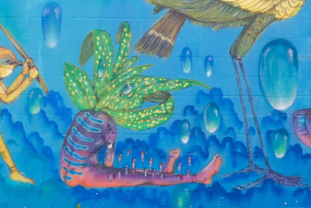 part of a mural, sitting person but with head made of green leaves floating and billowing in the blue water