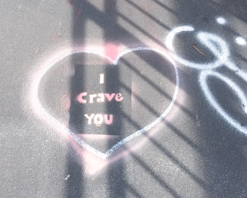 text graffiti on the williamsburg bridge pavement that says I crave you, written inside a large white heart