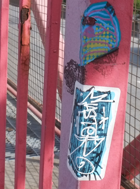 slaps, sticker graffiti on a pole on railings of a bridge