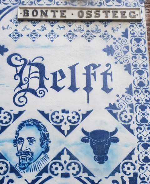 street sign for bonte ossteeg with mural, word delft in the mural, blue and white
