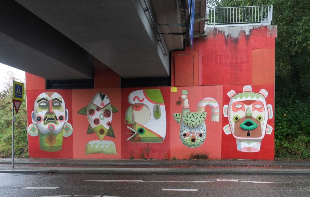 mural by finok, bright red background, 3 faces, one fish pointing upwards