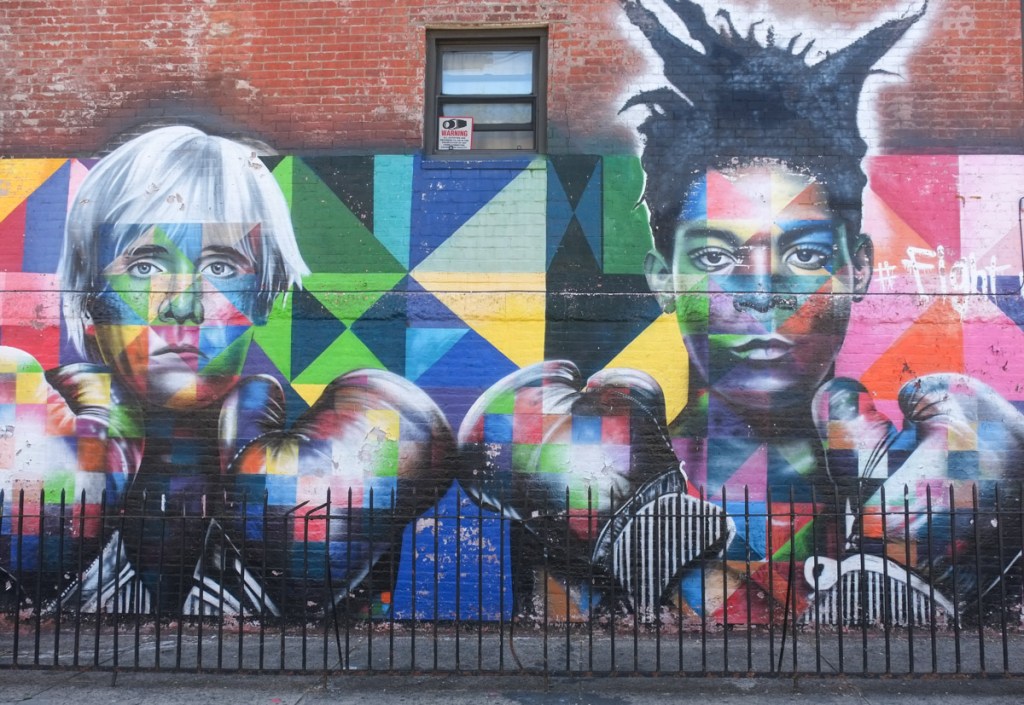 kobra multicoloured mural of andy warhol and jean michel basquiat in boxing shorts and boxing gloves, with arms crossed in front of themselves, mural at bedford and ninth in williamsburg new york city