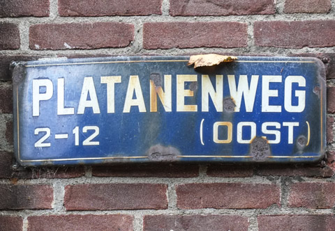 Blue metal sign affixed to brick building, street sign, Platanenweg, in Amsterdam