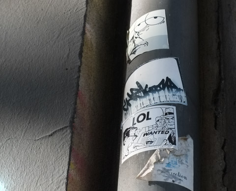three black and white stickers on a pole. 