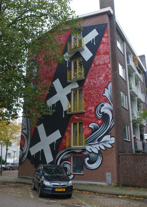 mural with symbol of Amsterdam on it, red background, black stripe with three white St. Andrews crosses