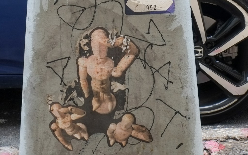 photo of group of three little wood mannequins posed in a salute, looking down from above