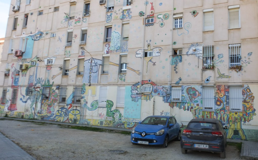 back of an apartment building, with many small scenes painted in one mural