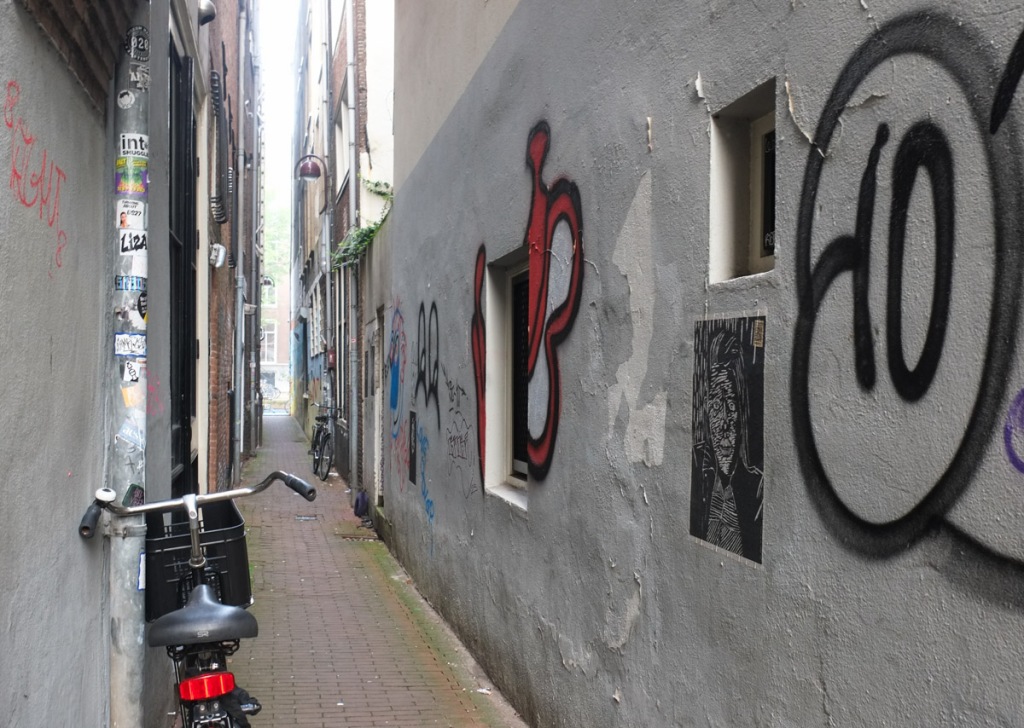 bicycles parked and leaning against walls in a very narrow alley