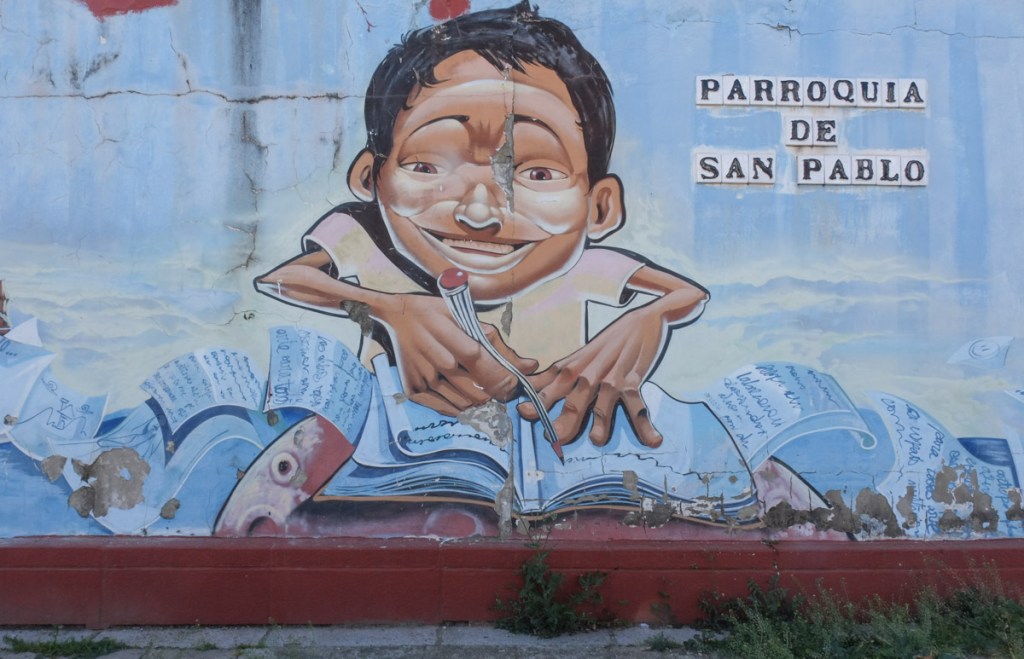 part of a mural, a boy with pencil and lots of papers that he's been drawing and writing on