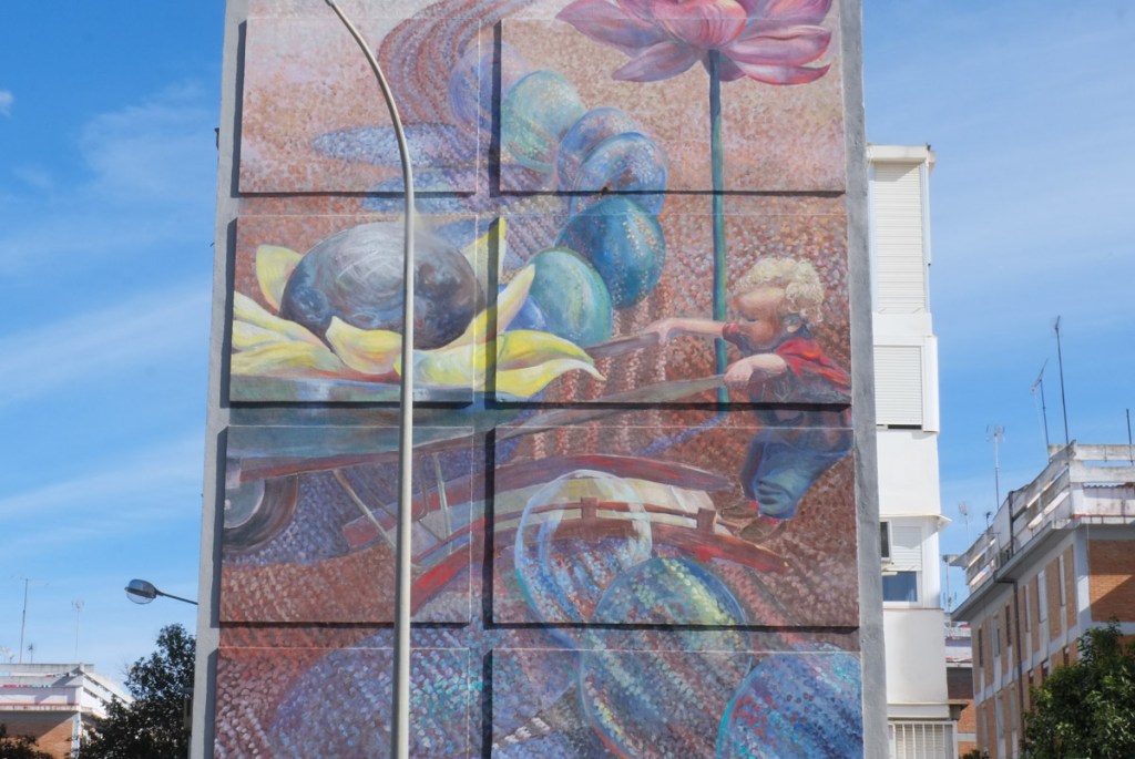 close up look at mural of child with a wheel barrow overflowing with things
