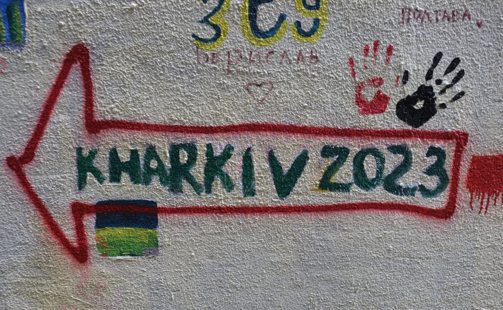 graffiti in an alley, a red arrow pointing left with word Kherson written in it