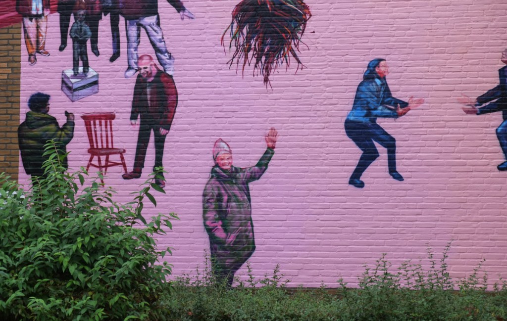 paink background, part of a larger mural, a woman waving