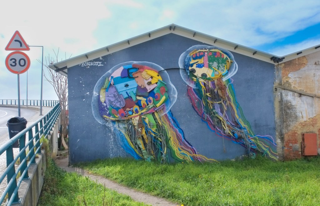 gargage, or small building, beside the road near the waterfront in Barreiro Portugal, with two large jellyfishes made of junk by street artist Bordalo