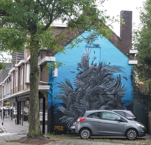 mural on the gable end of a building, blue background, a group of blackbirds all huddled together, by daze two