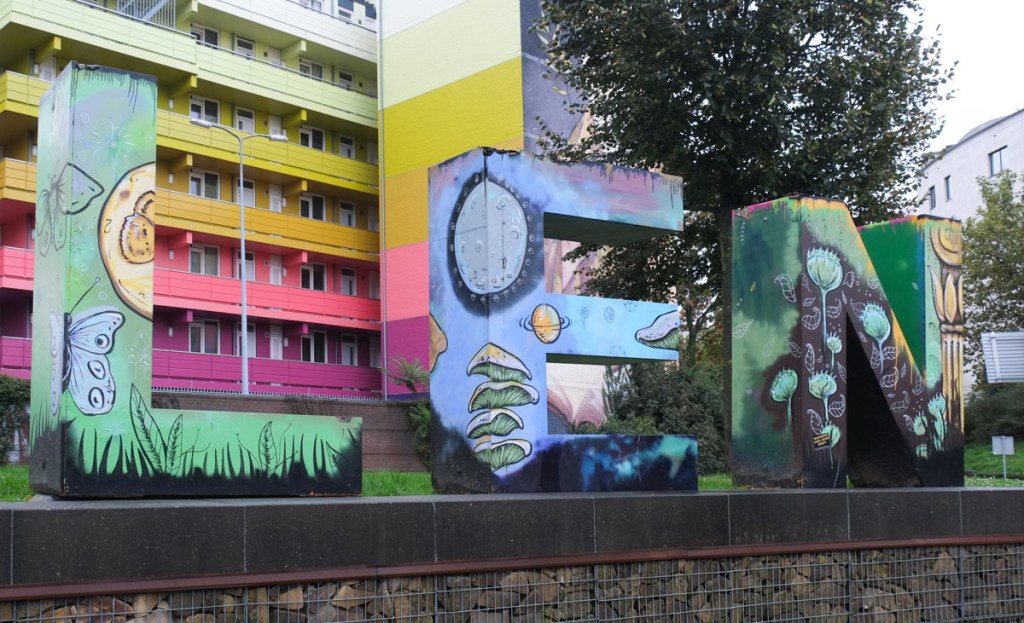 last three letters of Heerlen sign, capital letters, L, E, and N, painted with butterflies, mushrooms, and flowers