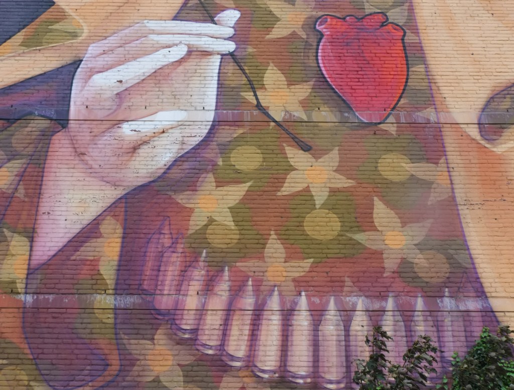 part of a larger mural, a person with a belt of bullets around their waist, and a shirt in camoflauge colours.