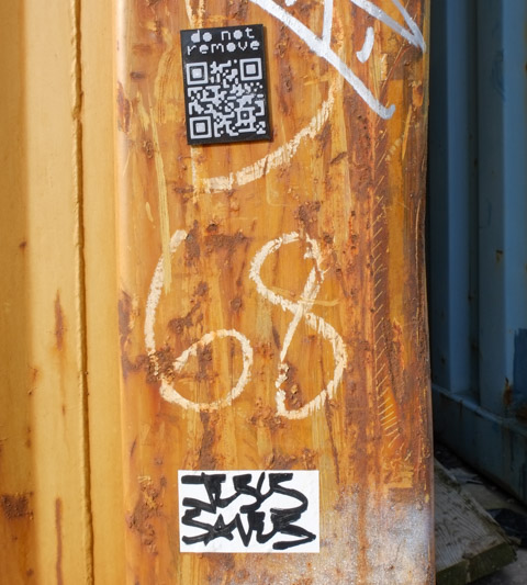2 stickers on a shipping container, one has a q r code and the words do not remove, the other is a hand written message, jesus saves