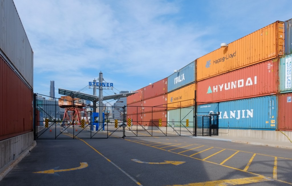exit from steiner studios in brooklyn, road with container wall on either side, three containers high 