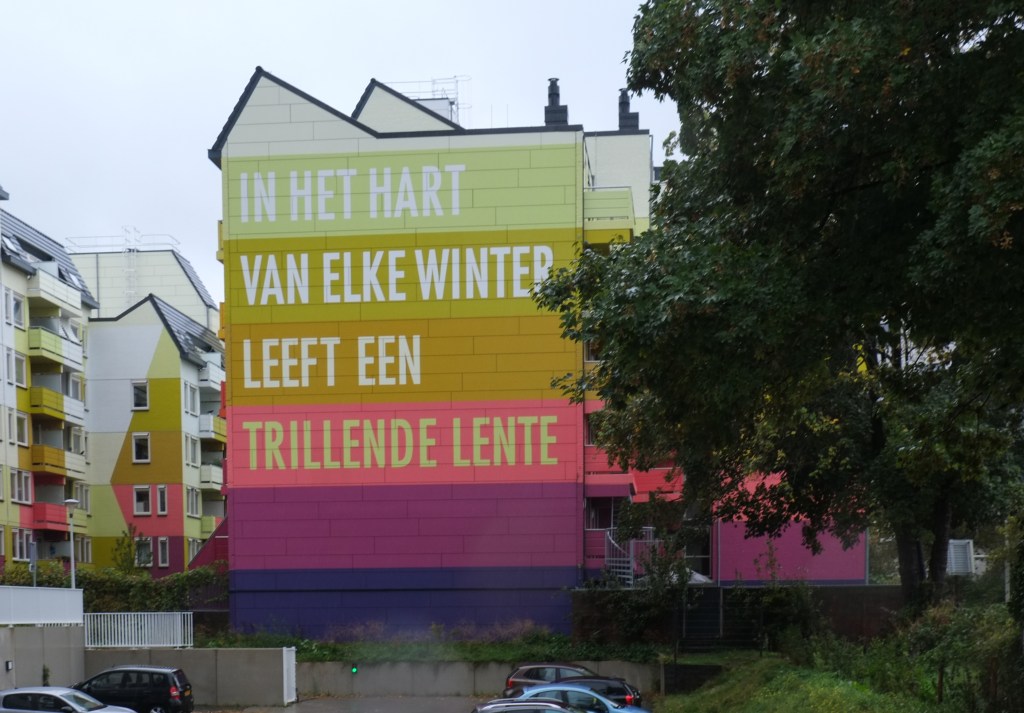 apartment building, residential, with stripes in yellow, oranges, and purples, with a text, a quote from Kahlil Gibran