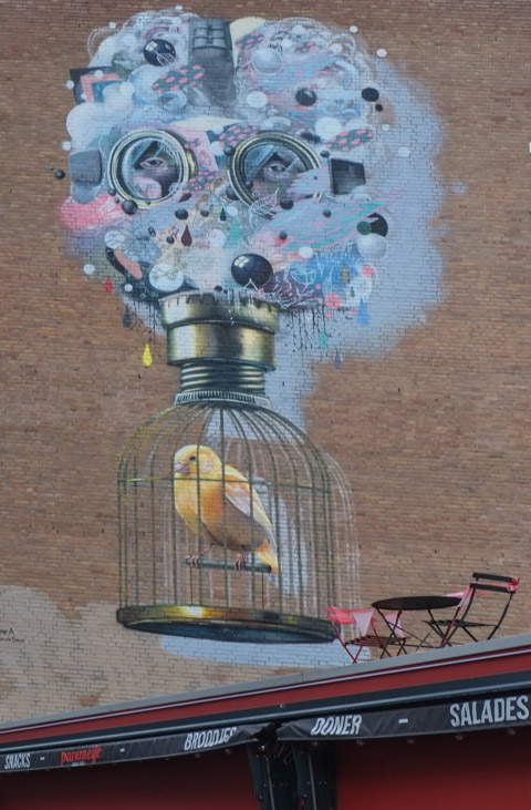 a yellow canary in a brass bird cage with a cloud of wisps, objects and a pair of eyes above it
