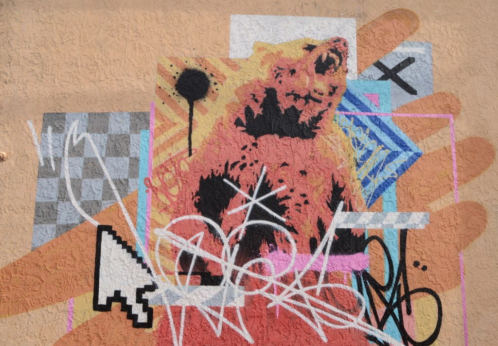 a mural with a brown bear, a white arrow that looks like a cursor on a computer screen