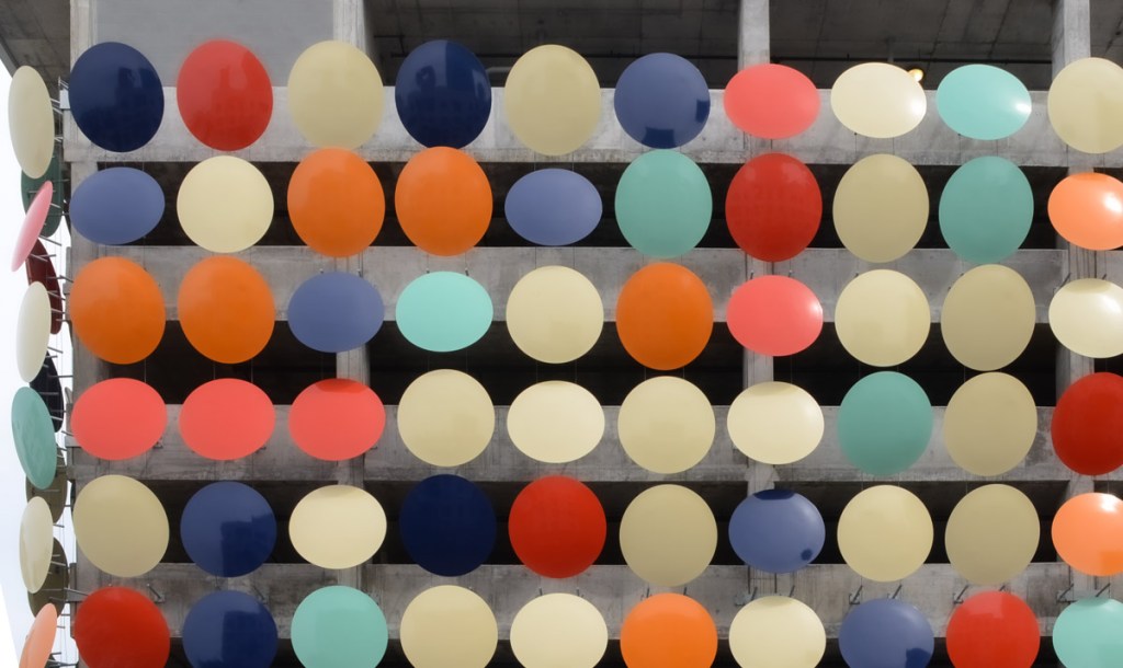 large metal discs, as art, cover the exterior of a parking garage, 119 discs, called dots, by artist Christian Moeller