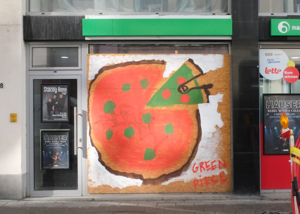 mural of a pizza, round with red sauce and green dots as topping, but one slice has green sauce and is the green piece