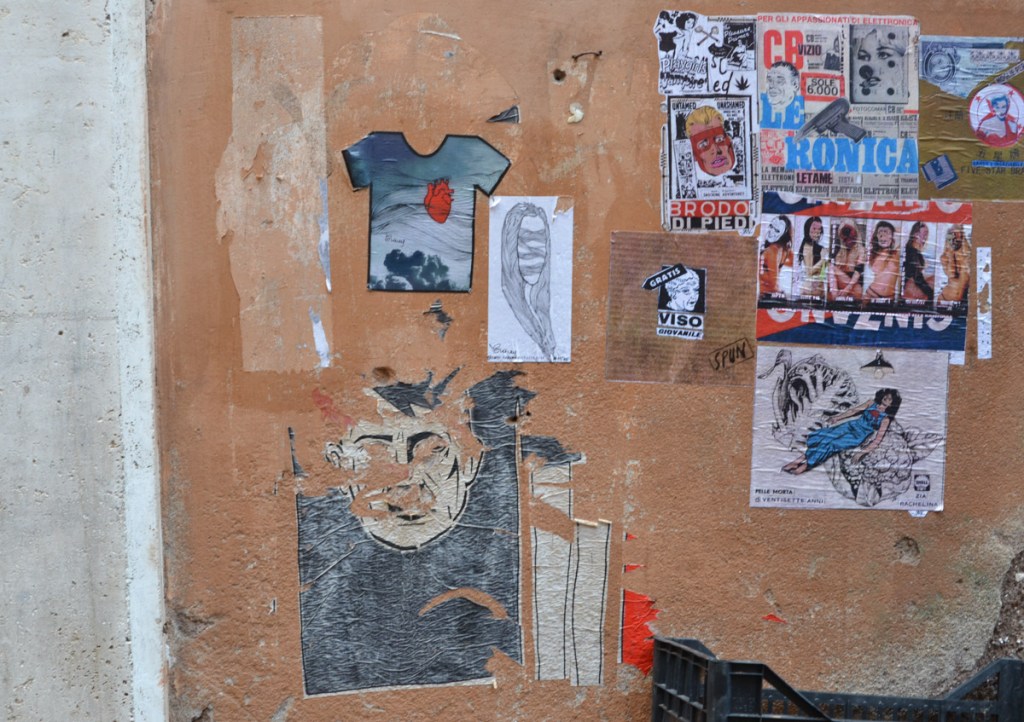 a wall with graffiti paper paste ups on it