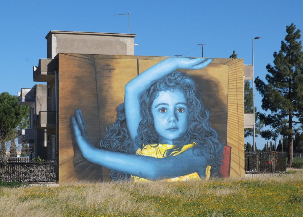 on the side of a residential building, a mural, portrait of a young girl in blue