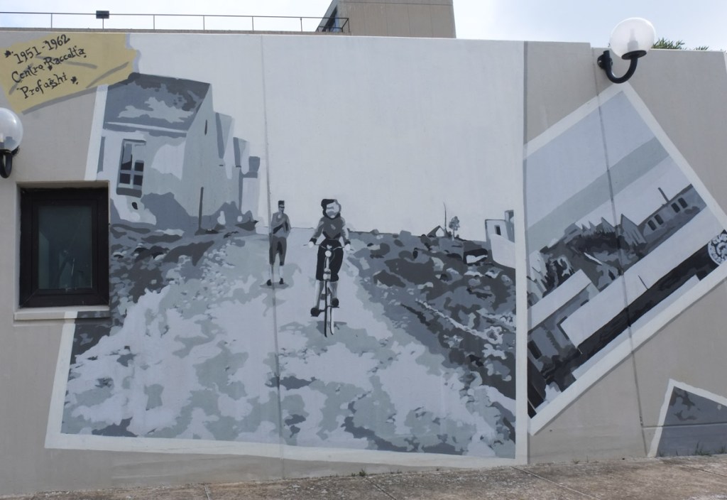 mural in shades of grey using images of old photographs from Camp 65 from WW2, one is a woman on a bicycle