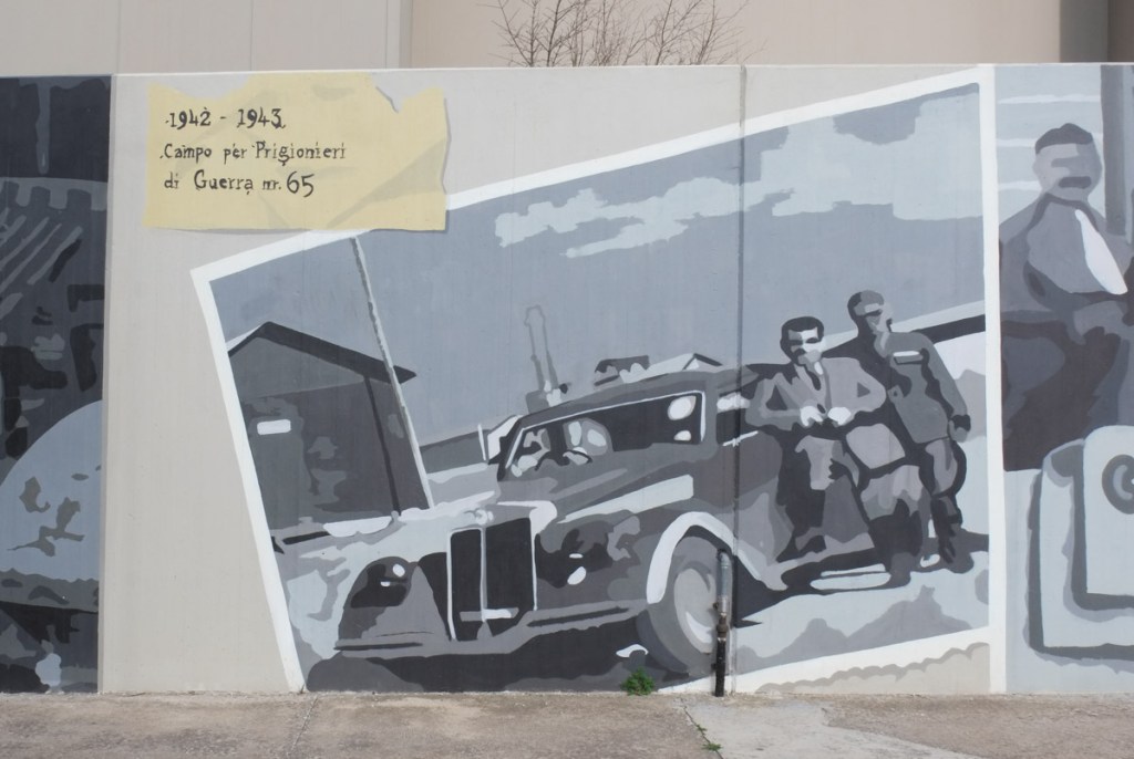 two men standing by a car from the 40s, black and white image on mural