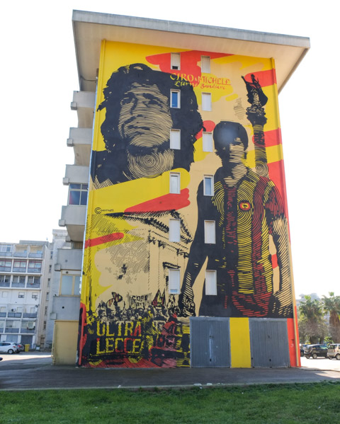 mural on the side of an apartment building of two football players in Lecce football club colours and uniforms, memorial wall to two who died in 1983, Michele Lorusso and Ciro Pezzella