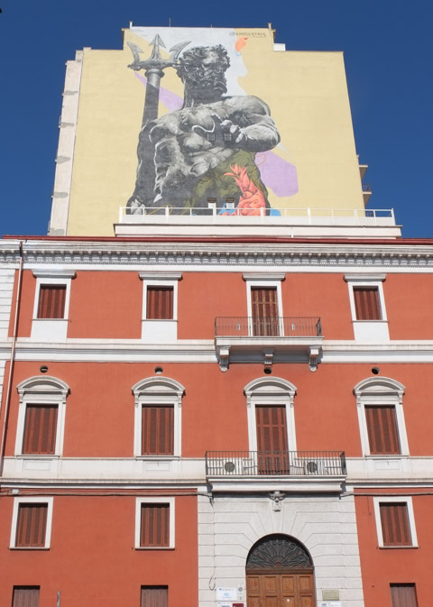 large mural of Roman god Neptune, on top of a reddish coloured building