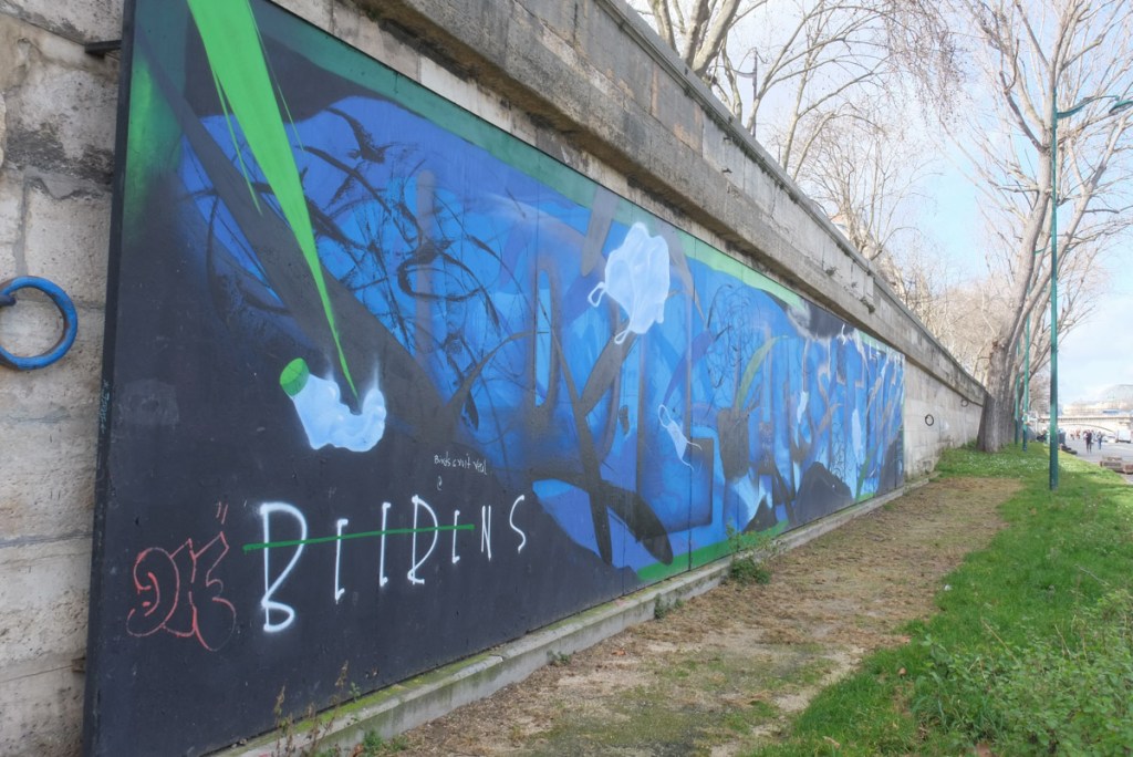 large mural in blues on a wall beside the River Seine