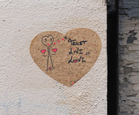 graffiti, small brown heart with stick figure made with hearts, text that says trust, live, love 