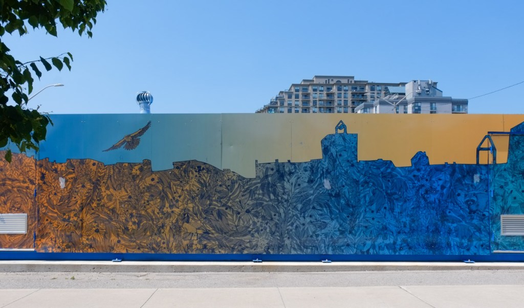 mural in orange and blue, barrie skyline filled in with images of flowers and feathers, and some animals