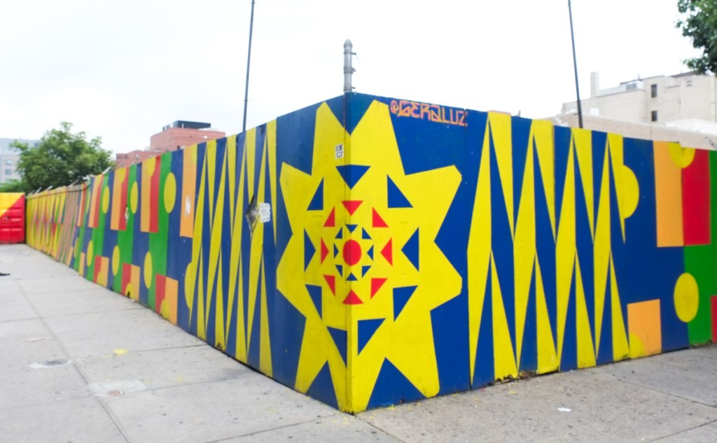 street art on hoardings in harlem new york, red, blue, and yellow geometrics with some green