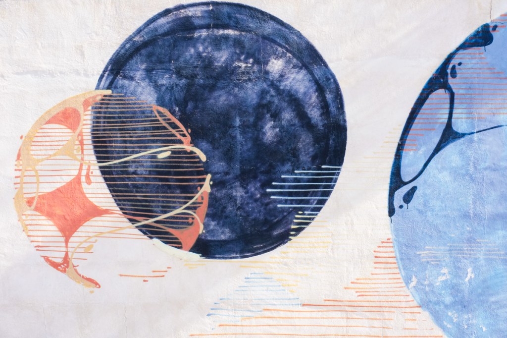 part of a mural, two blue circles, also a partially drawn circle, in orange