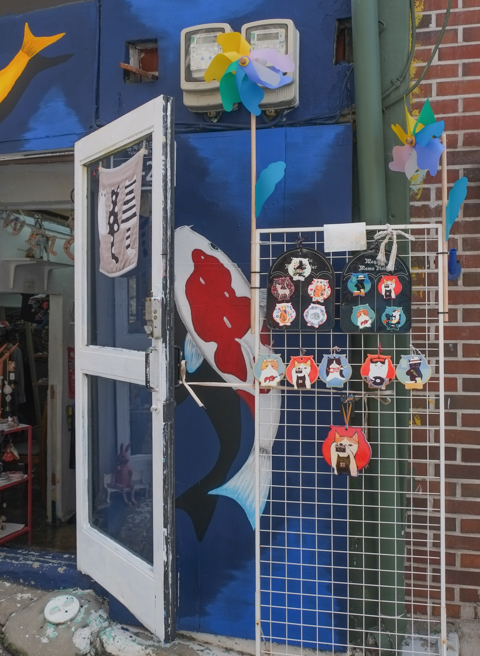 fish painted on bright blue background, around door of a store